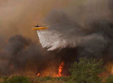 A helicopter drops water on a fire near the entrance to The Cliffs on the south east side Possum Kingdom Lake, Texas on Tuesday, August 30.