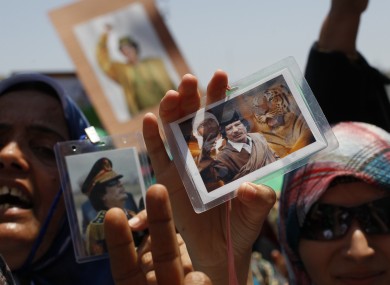 Libyan women show their badges with portraits of Gaddafi during a government-organised media tour in June 2011.