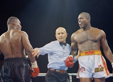 Legendary referee Mills Lane intervenes a mid-round conferring session between Tyson and Ruddock.