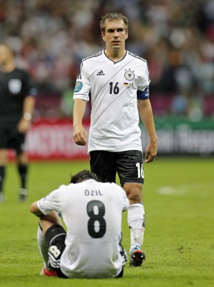 Germany's Mesut Oezil, down, and Philipp Lahm are dejected after the Euro 2012 semi-final.