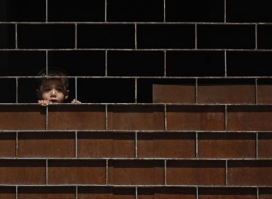 A young Syrian boy watches friends playing at a school where they have sought refuge.