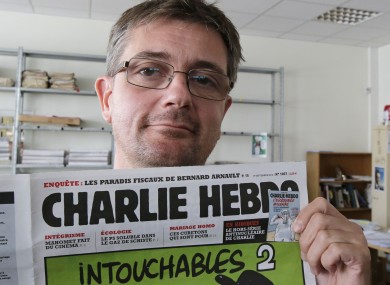Publishing director of the satiric weekly Charlie Hebdo, Charb, displays the front page of the newspaper as he poses for photographers in Paris