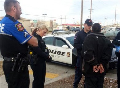 This image was provided by the Rapid City police officer Ron Terviel, left, and officer Carmen Visian, right as paramedics check a hit-and-run suspect.