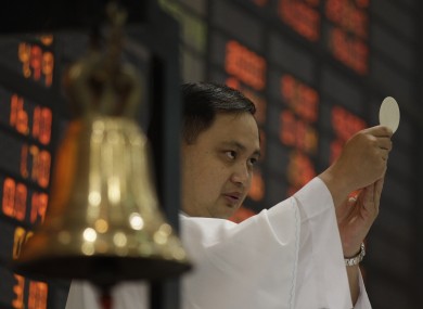 A Catholic priest makes an offertory during a mass before the start of the first day of trading at Philippine Stock Exchange.