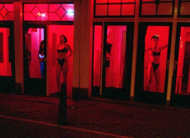 FILE-Prostitutes stand behind red-lit windows, waiting for customers in Amsterdam's Red Light district