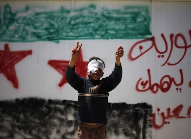 A 10-year-old Syrian refugee makes a victory sign in front of a wall at Zaatari refugee camp in Jordan