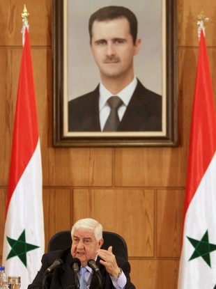 Syrian Foreign Minister Walid al-Moallem speaks during a press conference beneath a portrait of President Bashar Assad in Damascus today.