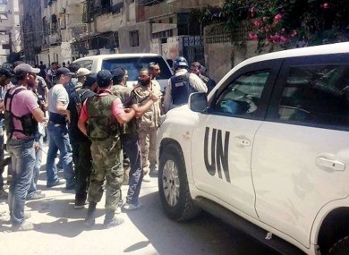A citizen journalism image provided by the United media office of Arbeen which has been authenticated, showing Syrian rebels escorted the UN investigation team, in Damascus countryside of Zamalka, Syria